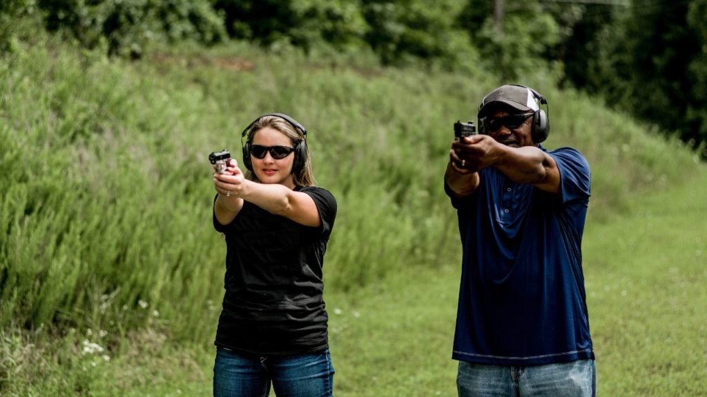 A woman and man aiming at shooting targets at an outdoor range.